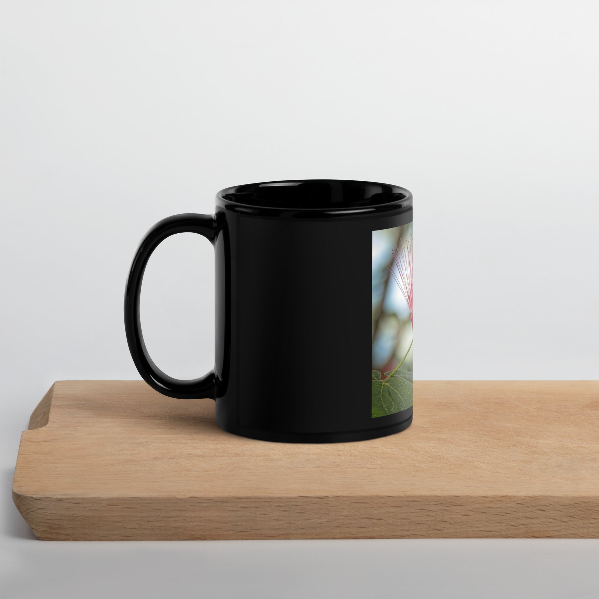 Black glossy ceramic mug with a vertical image of red powder puff flower from Calgary Zoo, Alberta.