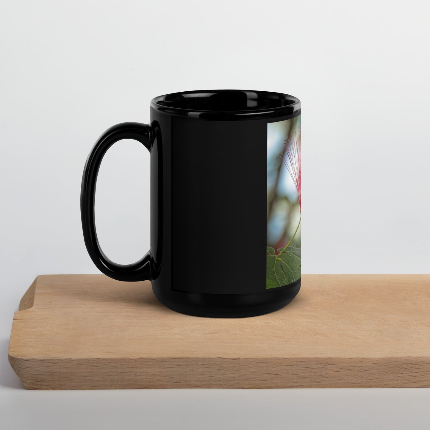 Black glossy ceramic mug featuring a vertical red powder puff flower photo, Calgary Zoo Alberta